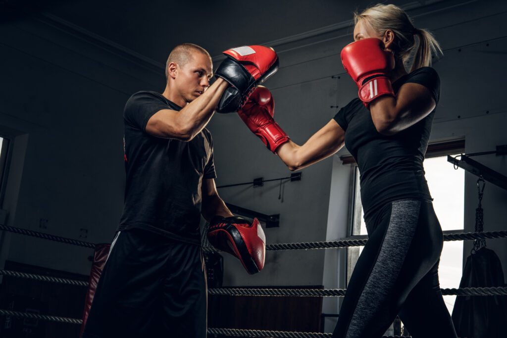 Sportive blond woman has boxing training with her experienced trainer.
